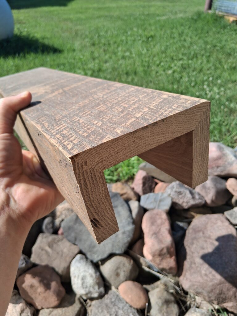 Close-up of a three-sided circle-sawn white oak box beam showing its hollow construction and miter locked corner joint